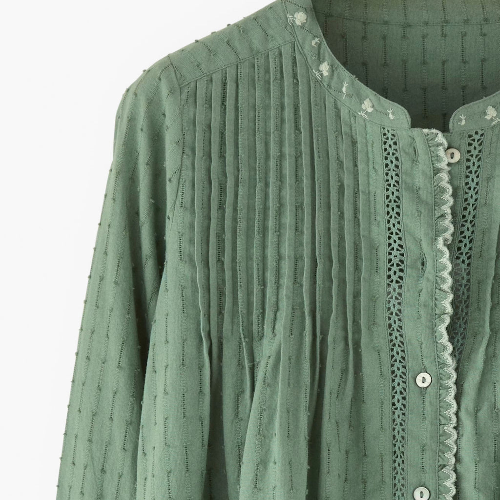Green textured shirt with lace trim on a white background
