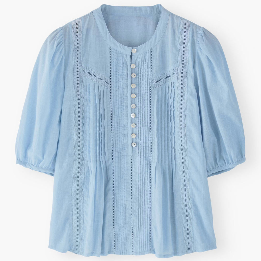Light blue blouse with button details on a white background