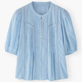 Light blue blouse with button details on a white background